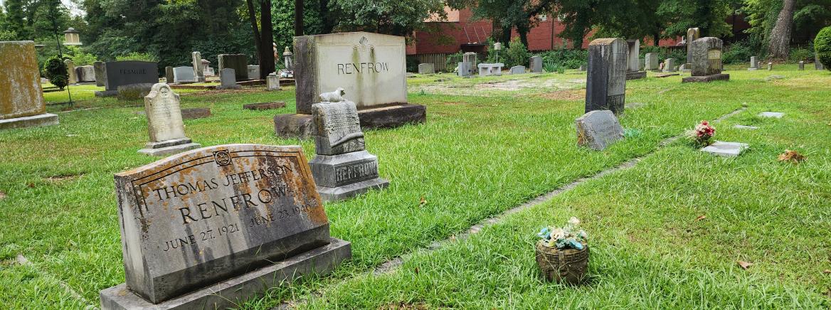 A view of several headstones in a cemetery on a sunny day.