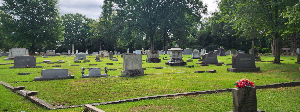 A view of several headstones in a cemetery on a sunny day.