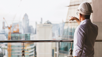 Image of a man wearing a hardhat looking over the city skyline.