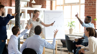 Successful cheerful businesswoman company head presenting new project to multi-ethnic young employees, diverse people voting raising hands or business coach giving presentation to clients in boardroom