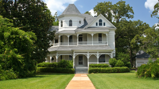 Photo of a white, two-story, historic home with large front porch.