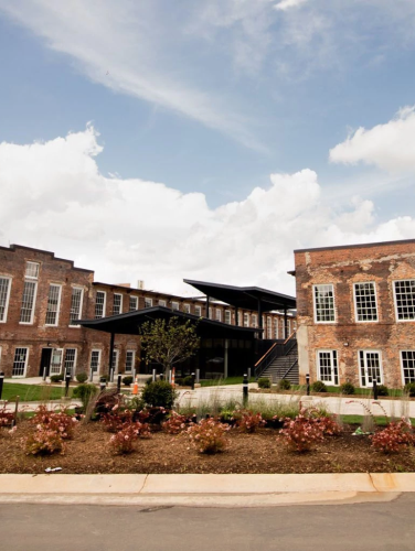 Two two-story brick buildings with a smoke stack on the left