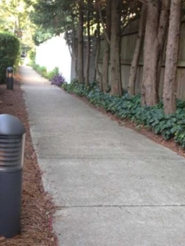 A long sidewalk with fencing on both sides